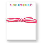 Notepad saying Alpha Omicron Pi with pink and white striped elastic band on a white background