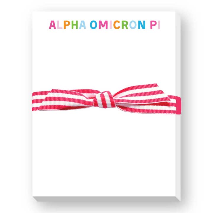 Notepad saying Alpha Omicron Pi with pink and white striped elastic band on a white background