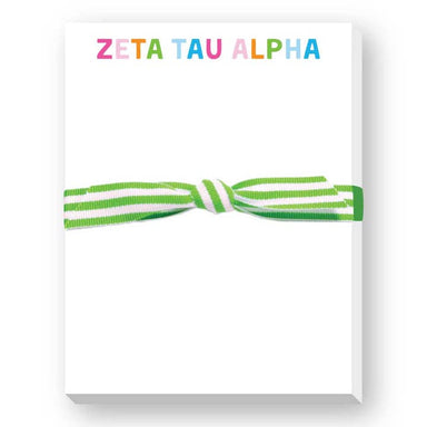 A white rectangular notepad or card with the words 'ZETA TAU ALPHA' printed at the top in multicolored letters, tied across the center with a green and white striped ribbon.