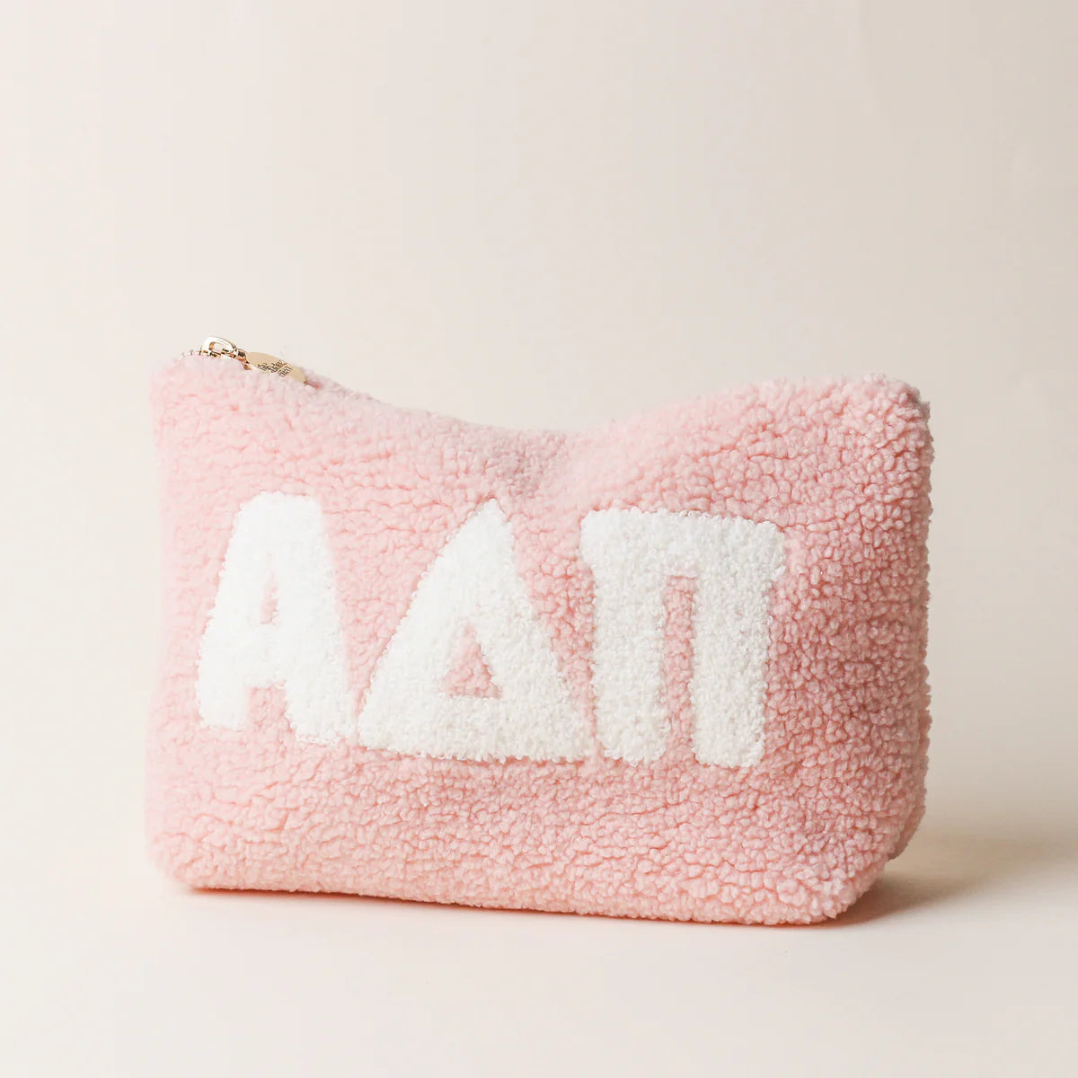Pink fluffy pouch with white sorority letters saying ADPi on a light beige background