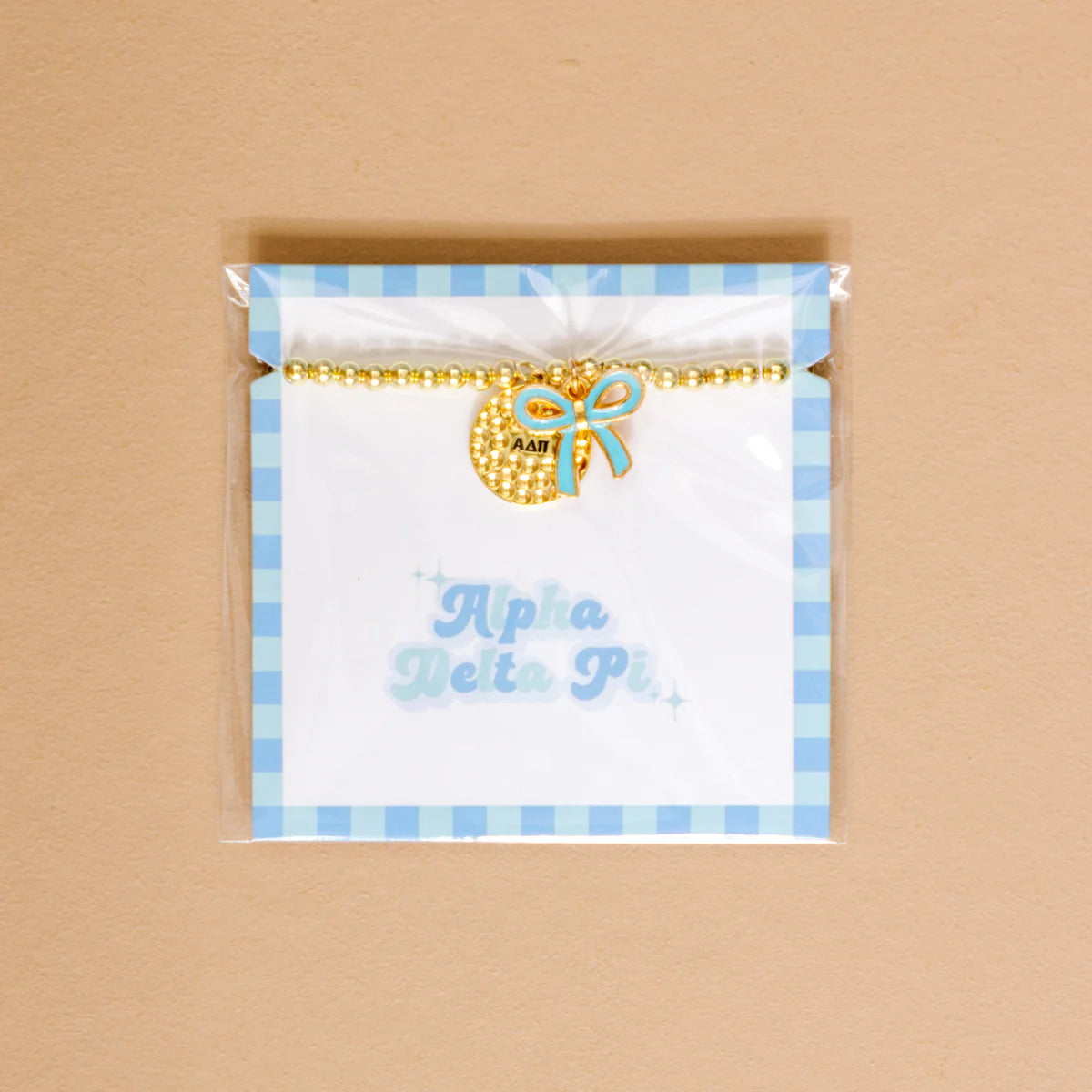 Gold bead bracelet with Alpha Delta Pi charm and a blue bow charm