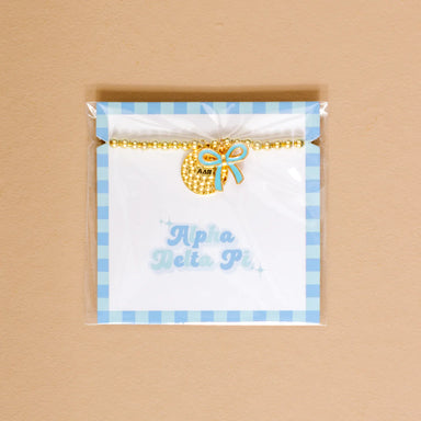 Gold bead bracelet with Alpha Delta Pi charm and a blue bow charm