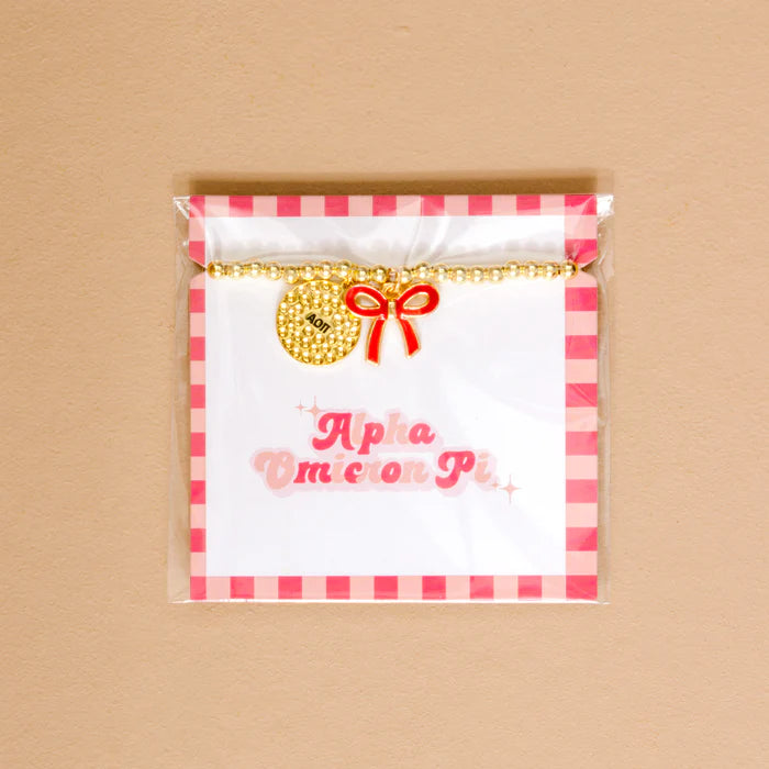 Gold bead bracelet with Alpha Omicron Pi charm and a red bow charm