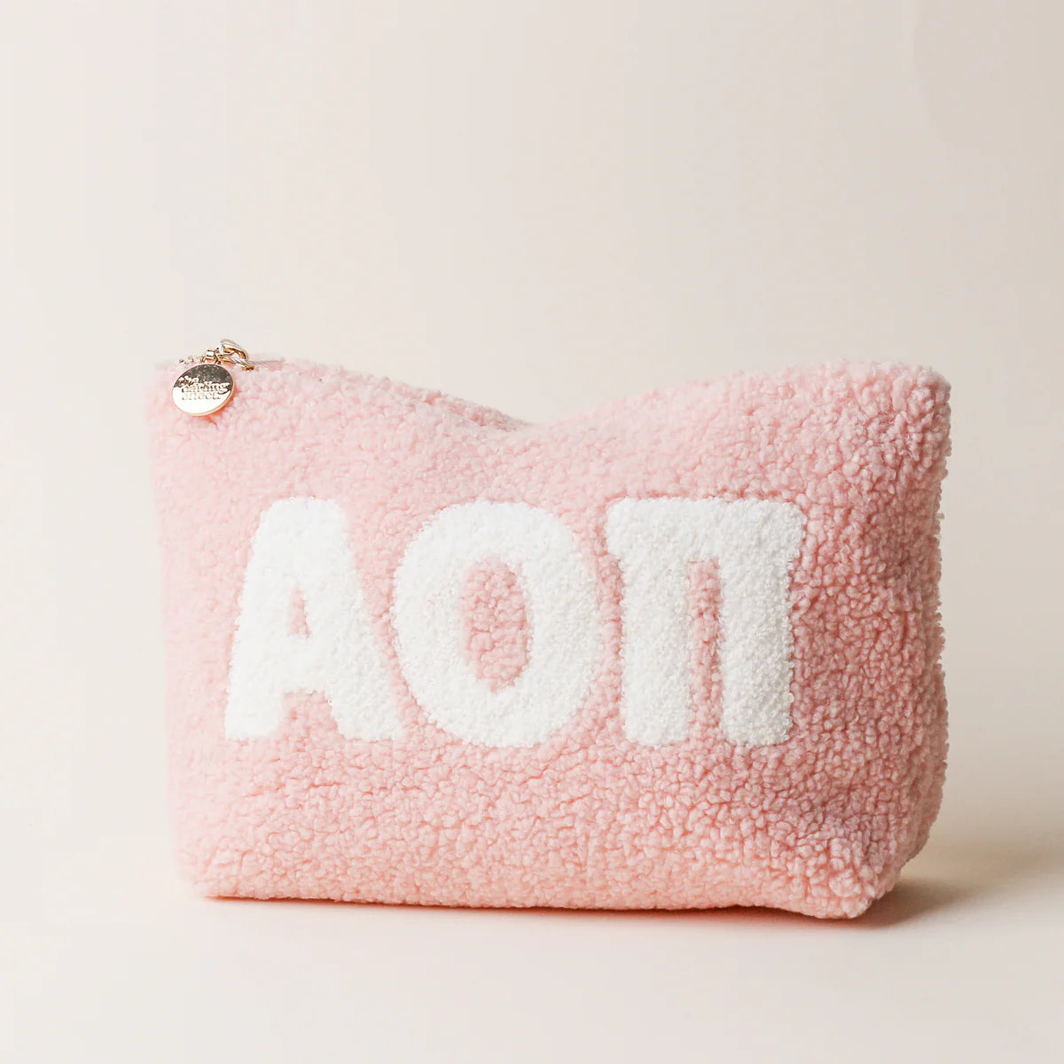 Pink fluffy pouch with 'AOPi' text on a light beige background