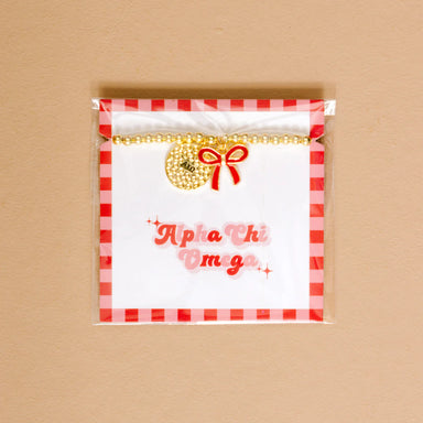 Gold bead bracelet with Alpha Chi Omega charm and a red bow charm