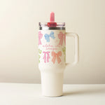 Tumbler with colorful bow designs on a beige background saying Alpha Chi Omega
