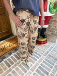Person wearing beige floral pants standing on a brick porch with a 'Welcome' mat.