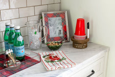 Kitchen counter with holiday-themed decor including red cups, green bottles, and plaid accents.