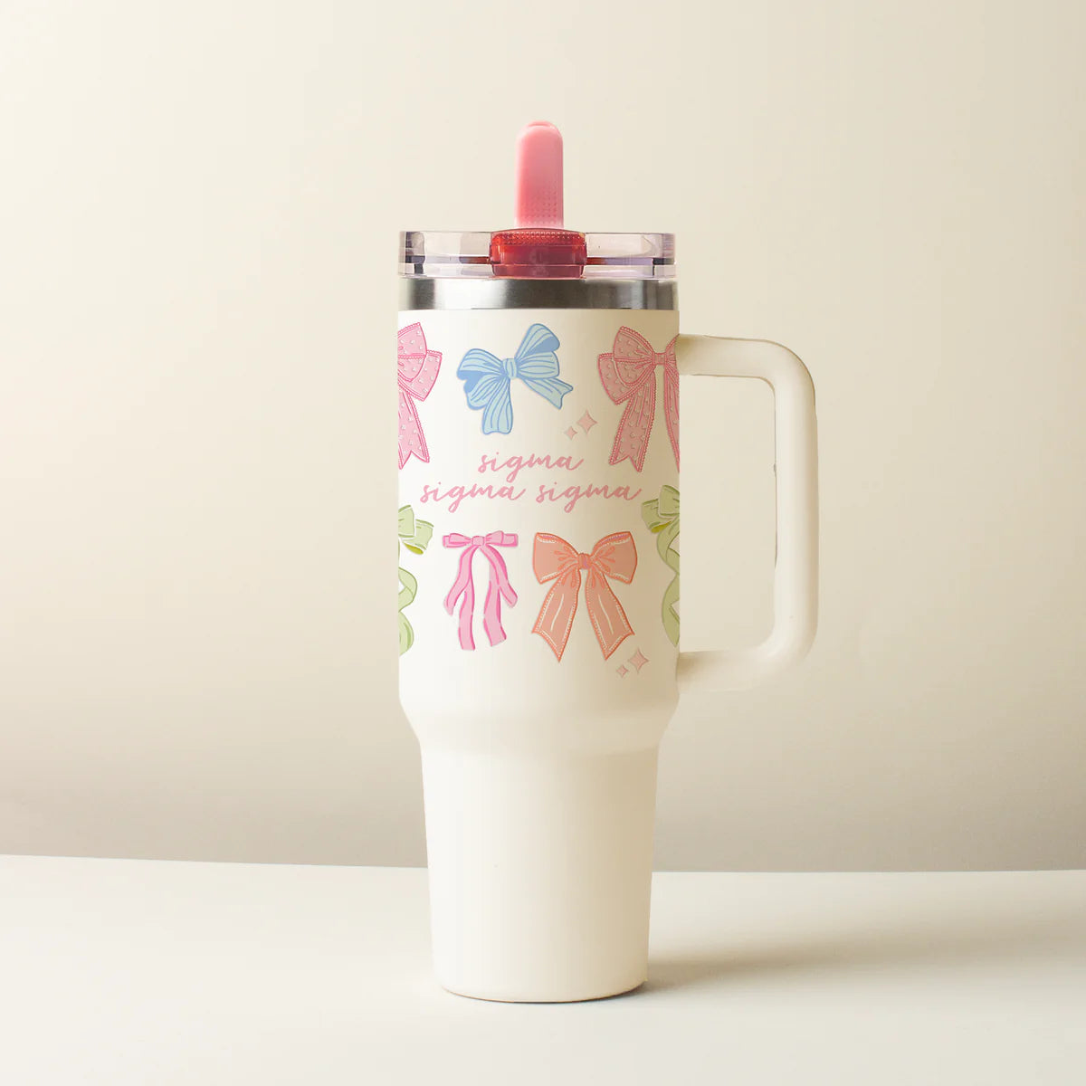 Tumbler with colorful bow designs  on a beige background saying Sigma Sigma Sigma