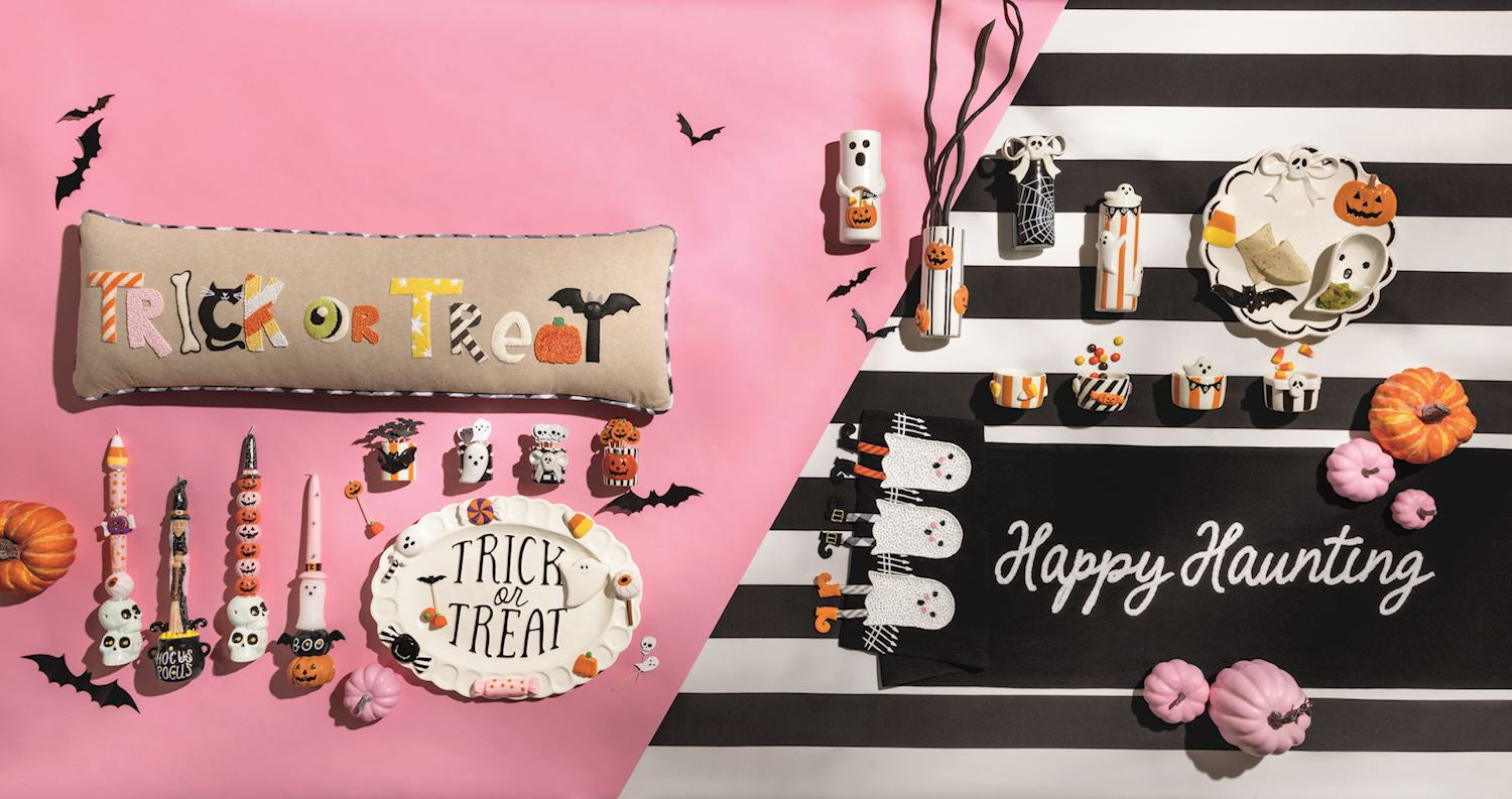Halloween-themed decor items including a pillow, candles, and a sign on a pink and black striped background.