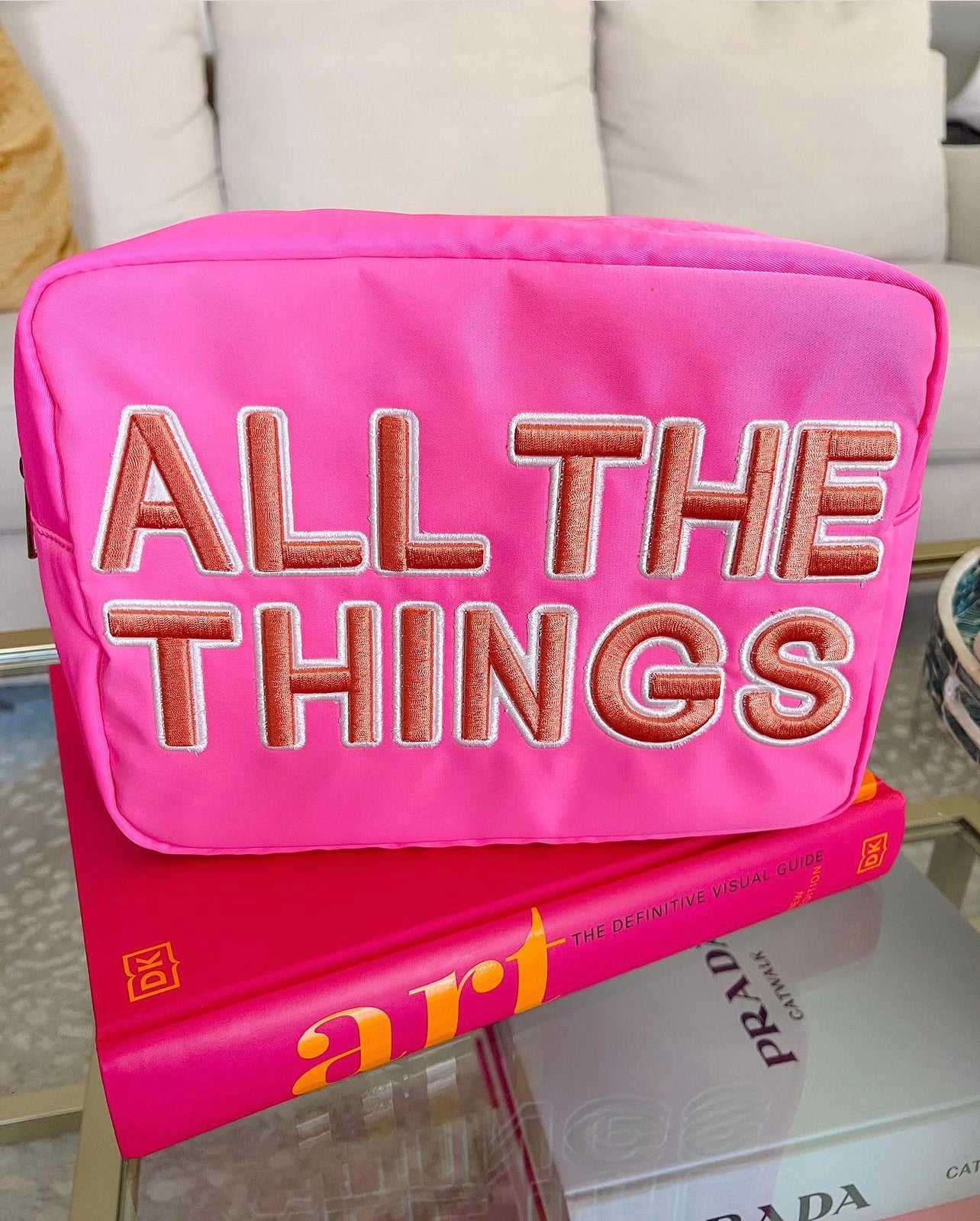 Photo of a hot pink XL canvas makeup bag saying “All the Things” on the front in peach appliqué letters that are sewn on 