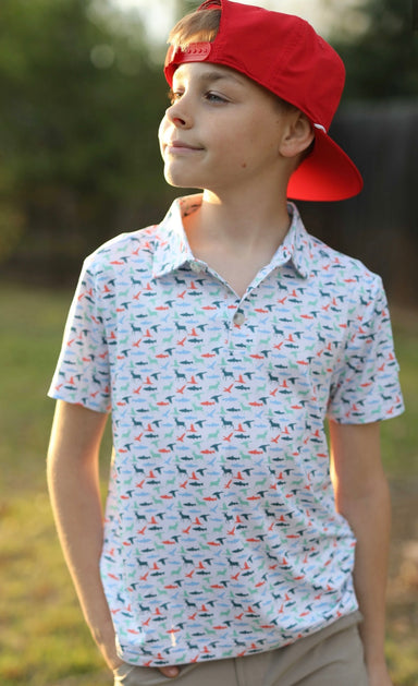 Photo of a male youth modeling white shirt features a  print of ducks, deer, and sharks in shades of orange, light blue, and green