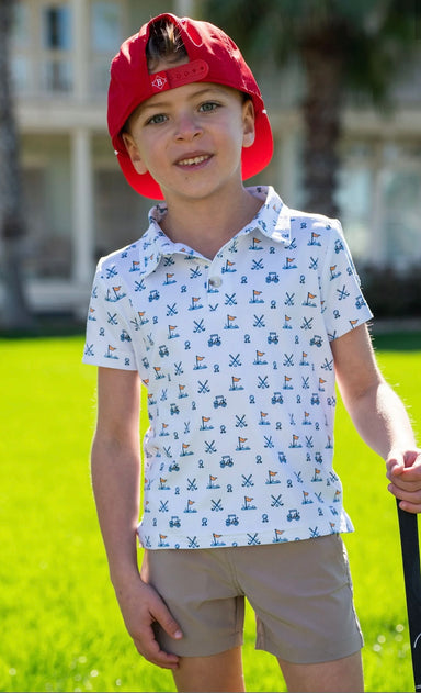 Photo of a male youth modeling our performance white polo featuring a fun print of a golf ball, cart, and putting green in shades of blue. 
