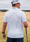 Photo of a man modeling the back of our performance white short sleeve polo featuring a fun print of a golf ball, cart, and putting green in shades of blue.