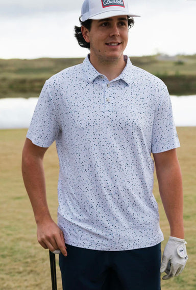 A man modeling the front of this white performance polo with a blue speckled pattern all over