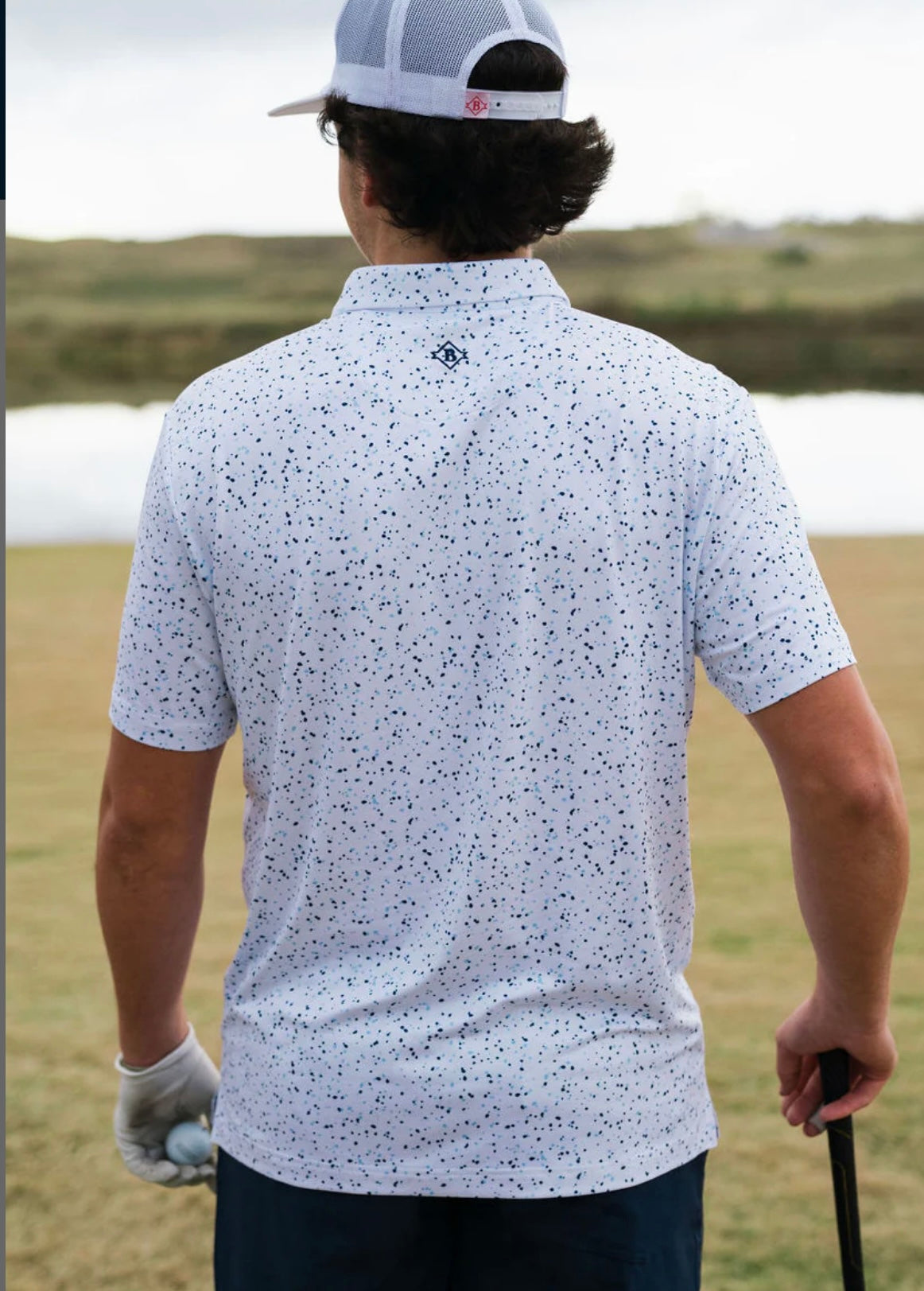 Photo of the back of this white performance polo with a blue speckled pattern all over