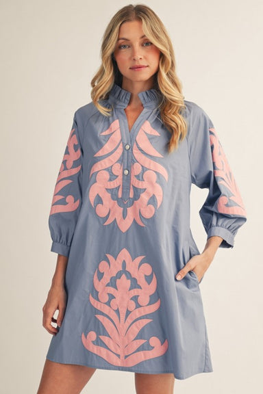 Woman wearing a blue dress with pink floral patterns on a plain background