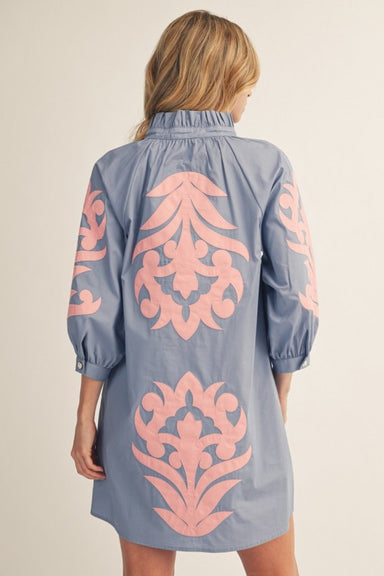 Woman wearing a blue dress with pink floral patterns on a beige background