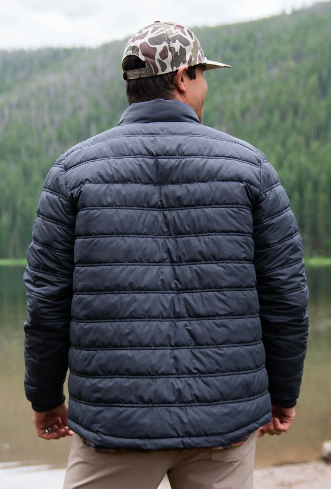 Man modeling a Men’s gun-metal gray puffer jacket in a horizontal quilting pattern