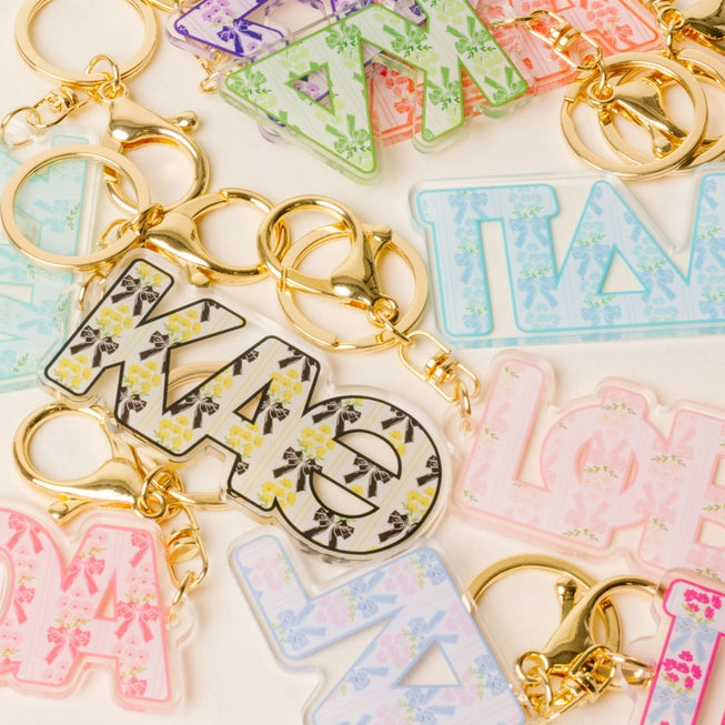 Colorful letter-shaped keychains with gold rings on a light background