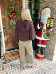 Person modeling the back of our leopard print pants standing on a brick sidewalk with a wooden door and doormat in the background.