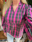 Close up photo of a pink plaid shirt with a v-neck, ruffled collar