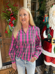 Woman in a pink plaid shirt standing in front of a decorated door with Christmas decorations.