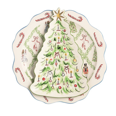 A Christmas-themed ceramic plate featuring a large green Christmas tree with ornaments and a gold star on the front, surrounded by a border of candy canes, bows, holly, and nutcracker illustrations.