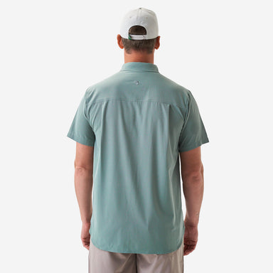 Man modeling the back of a sage green shirt and white cap on a plain background