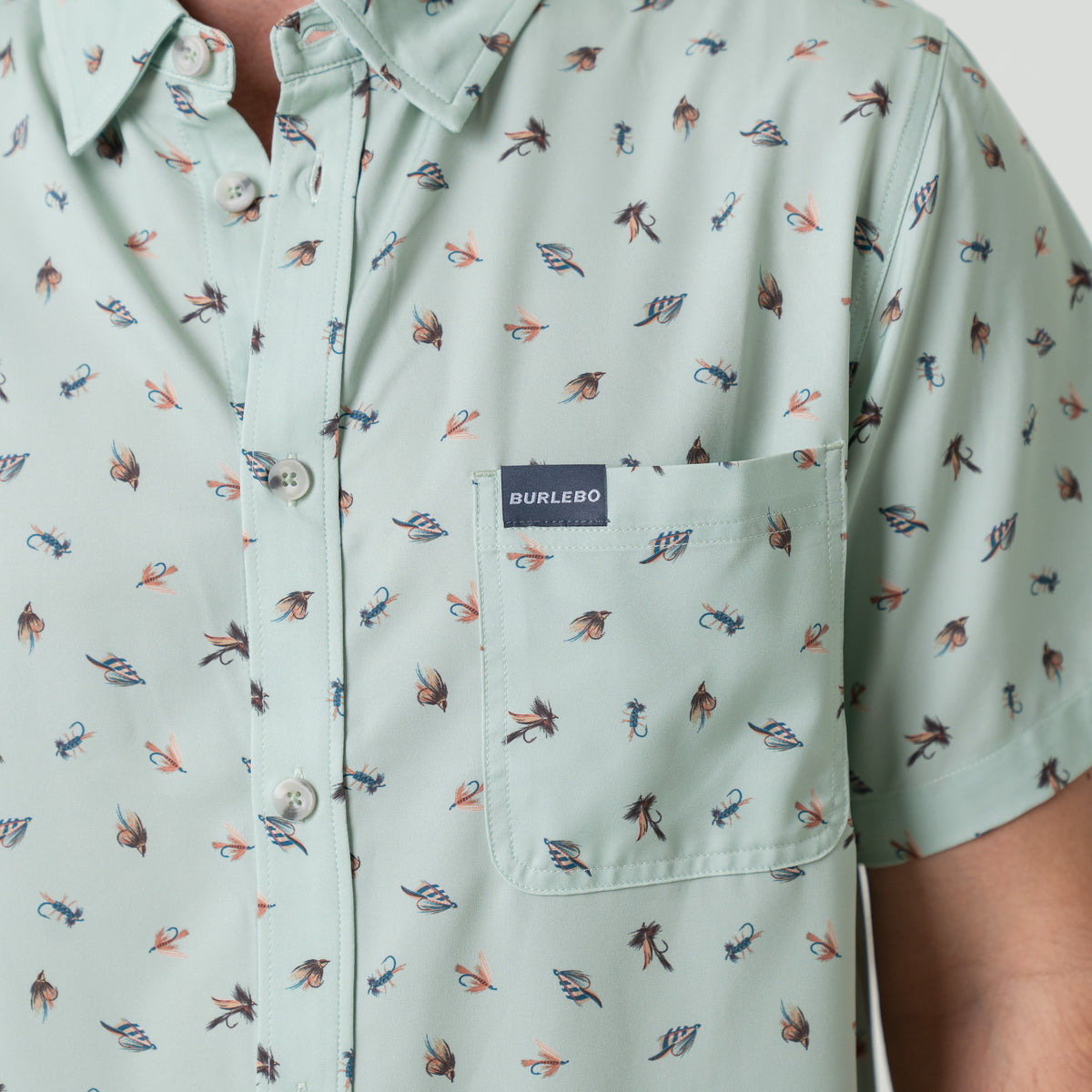 Light green button down shirt with small pattern of fishing lures and Burlebo label on a person
