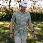 Man wearing a sage green short sleeve polo with a small lightning rod pattern all over
