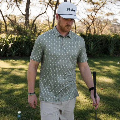 Man wearing a sage green short sleeve polo with a small lightning rod pattern all over