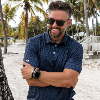 A man modeling a navy short sleeve polo with the American flag in shades of navy in an all over pattern.