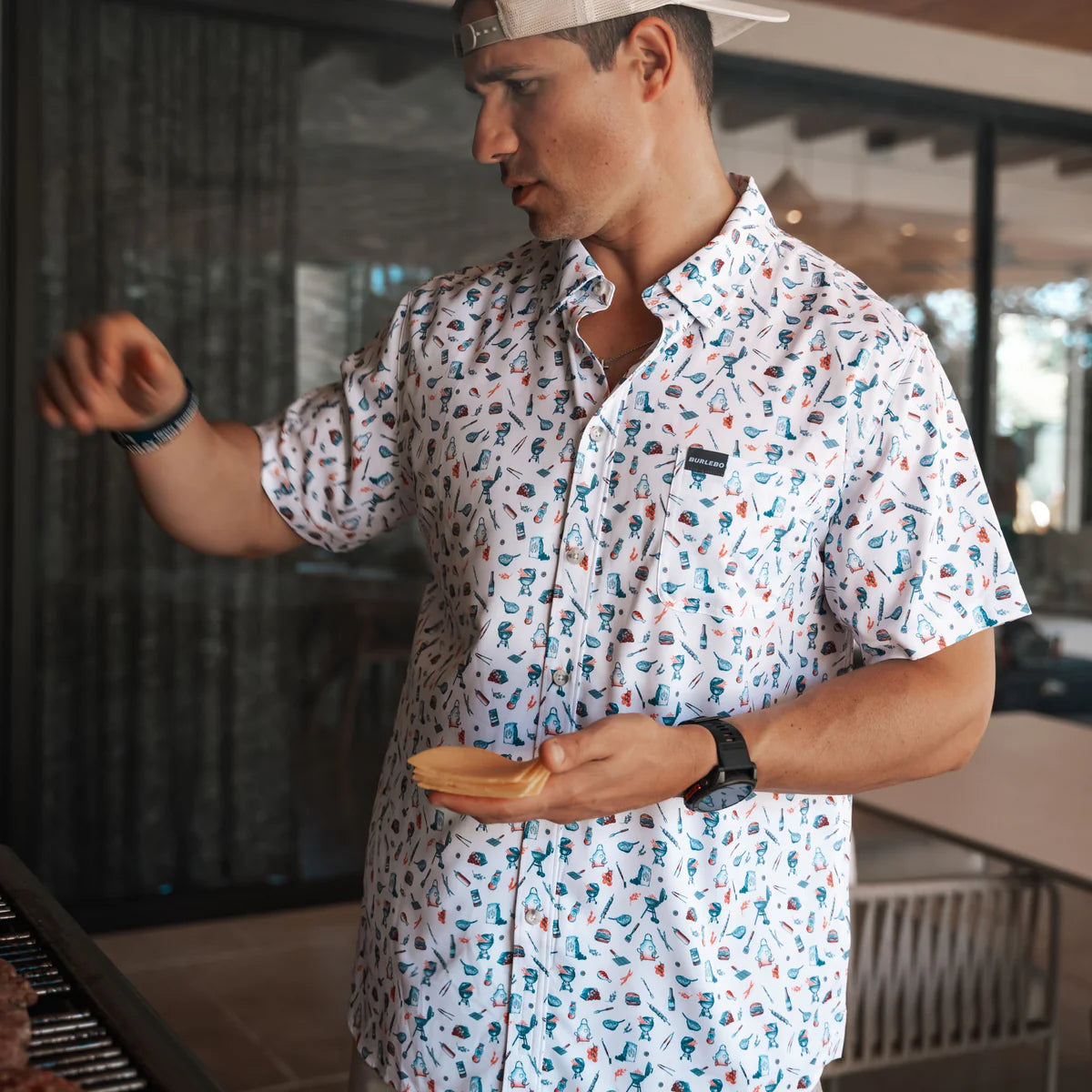Man modeling a white button down short sleeve shirt with small grilling symbols in an all over pattern