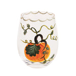 A clear stemless wine glass featuring a hand-painted illustration of an orange pumpkin with a dark green leaf and gold vine details, set against a plain white background.