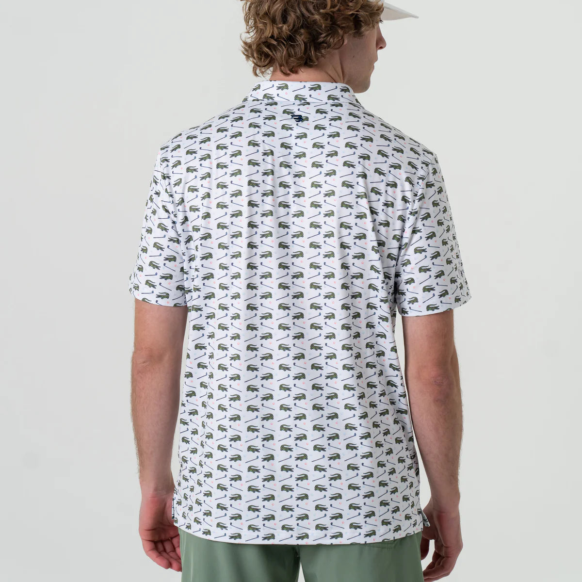 A man modeling the back of a white short sleeve polo with green alligators and golf clubs in an all over pattern