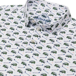 Up close photo of a white short sleeve polo with green alligators and golf clubs in an all over pattern