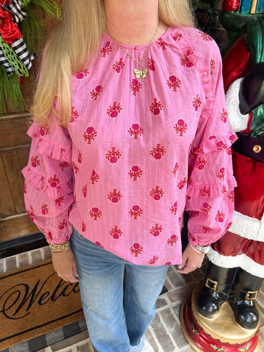Person wearing a pink blouse with red patterns in a festive indoor setting.